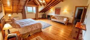 Ein Zimmer mit Bett, Schlafsofa, Holzboden, Heizkörper und Fenster.