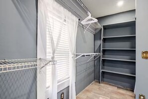 A room with a metal shelf unit, a white curtain, and a grey wall.