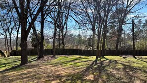 A wooded area with trees and a wooden fence. - Comfortable 4BR•2 King Beds• Near Arbor Place Mall (Douglasville)