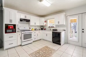 A kitchen with white cabinets, a stove, microwave, and dishwasher. - Comfortable 4BR•2 King Beds• Near Arbor Place Mall (Douglasville)