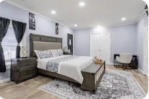 Quarto com cama, mesas de cabeceira, escrivaninha e cadeira.