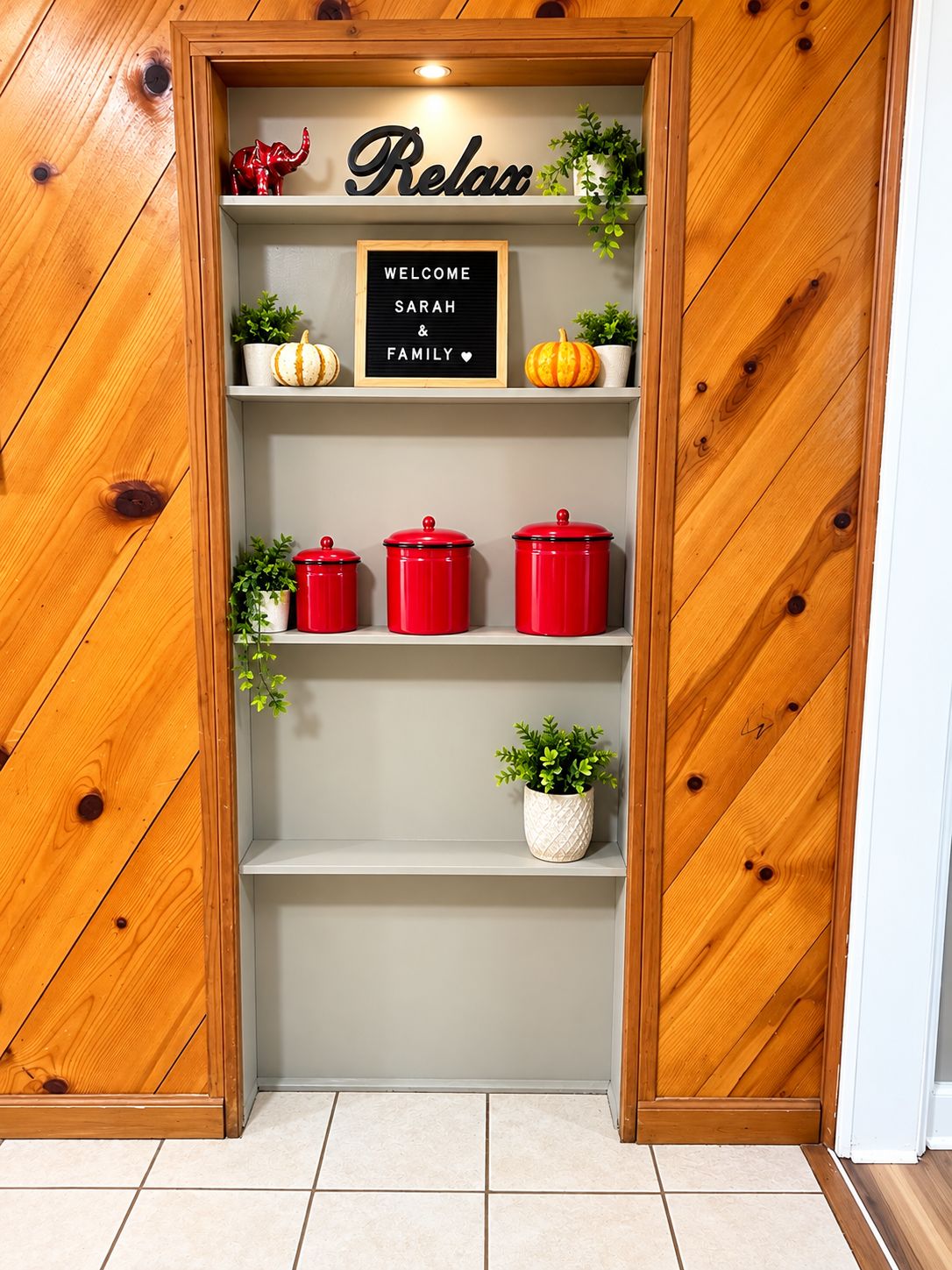 A wooden wall with a welcome sign, red storage containers, and potted plants.