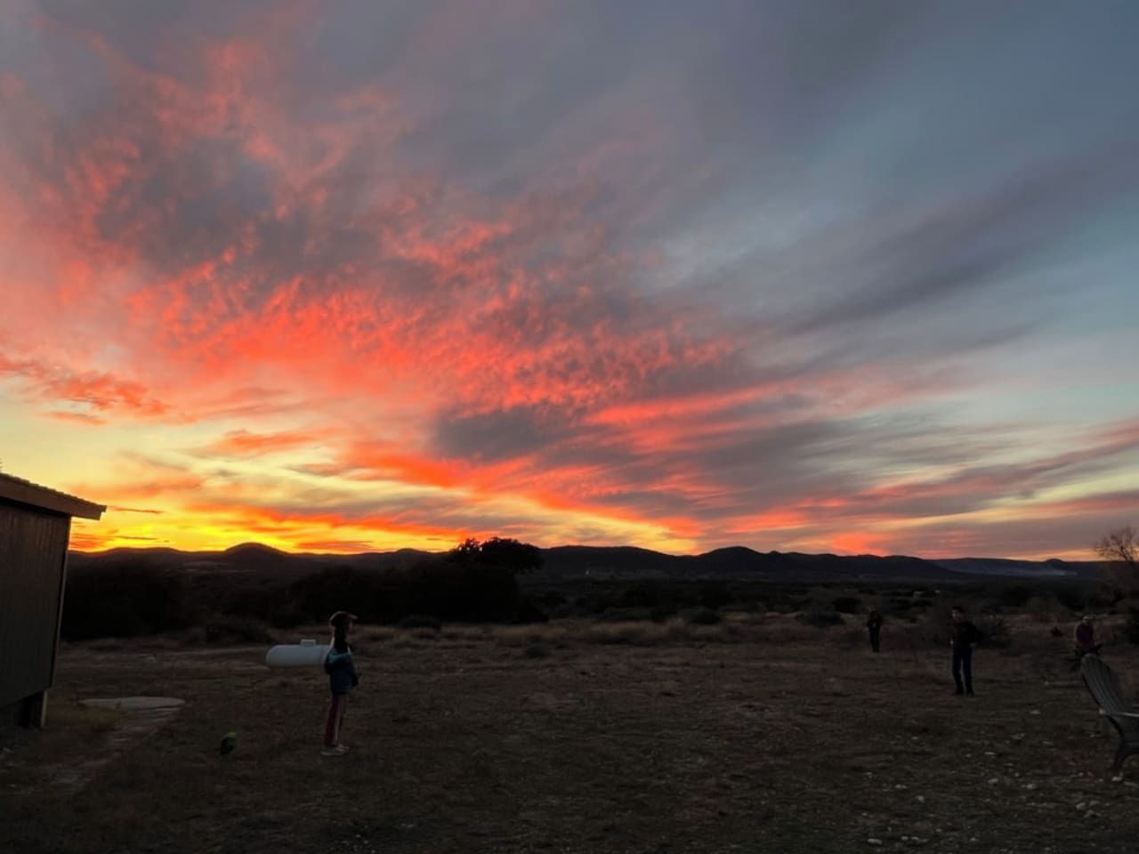 Un'area esterna con cielo al tramonto, un edificio e persone.