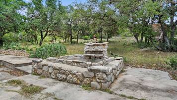 A stone structure with steps leading up to it, surrounded by greenery and trees.