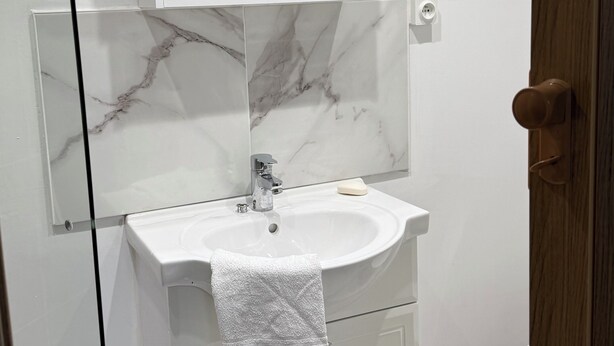 A bathroom with a white sink, marble backsplash, and a wooden door. - Vilabahia, a peaceful getaway just a stone's throw from the sea (Sète)