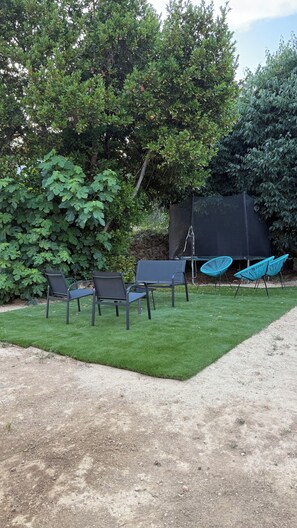 A grassy outdoor area with a seating arrangement, including chairs and a hammock.