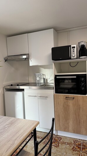 A compact kitchen with a microwave, coffee maker, and a built-in oven.
