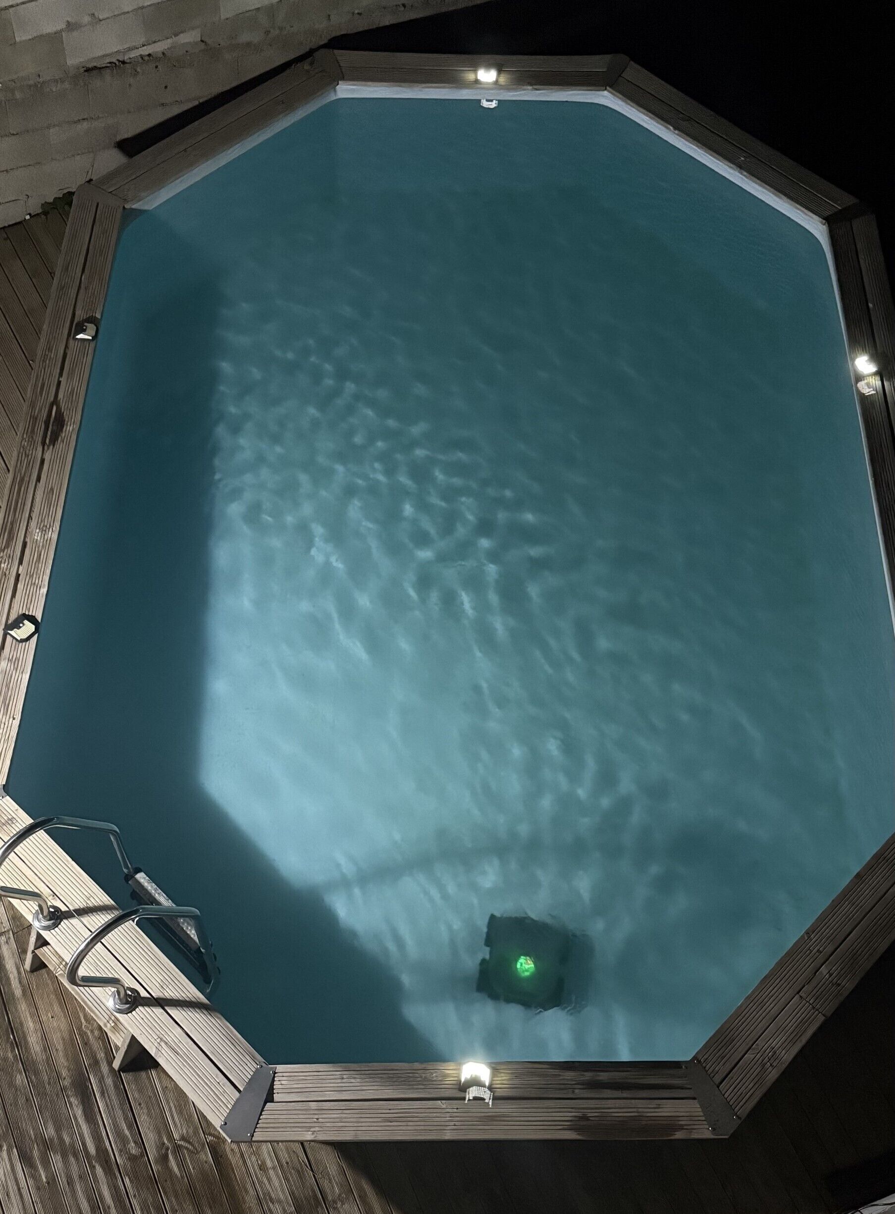 Une grande piscine octogonale entourée d’une terrasse en bois.