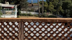 A balcony with a view of the sea, a palm tree, and a building with a satellite dish. - Vilabahia, a peaceful getaway just a stone's throw from the sea (Sète)