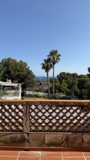 A balcony with a view of the sea, a palm tree, and a building with a satellite dish. - Vilabahia, a peaceful getaway just a stone's throw from the sea (Sète)