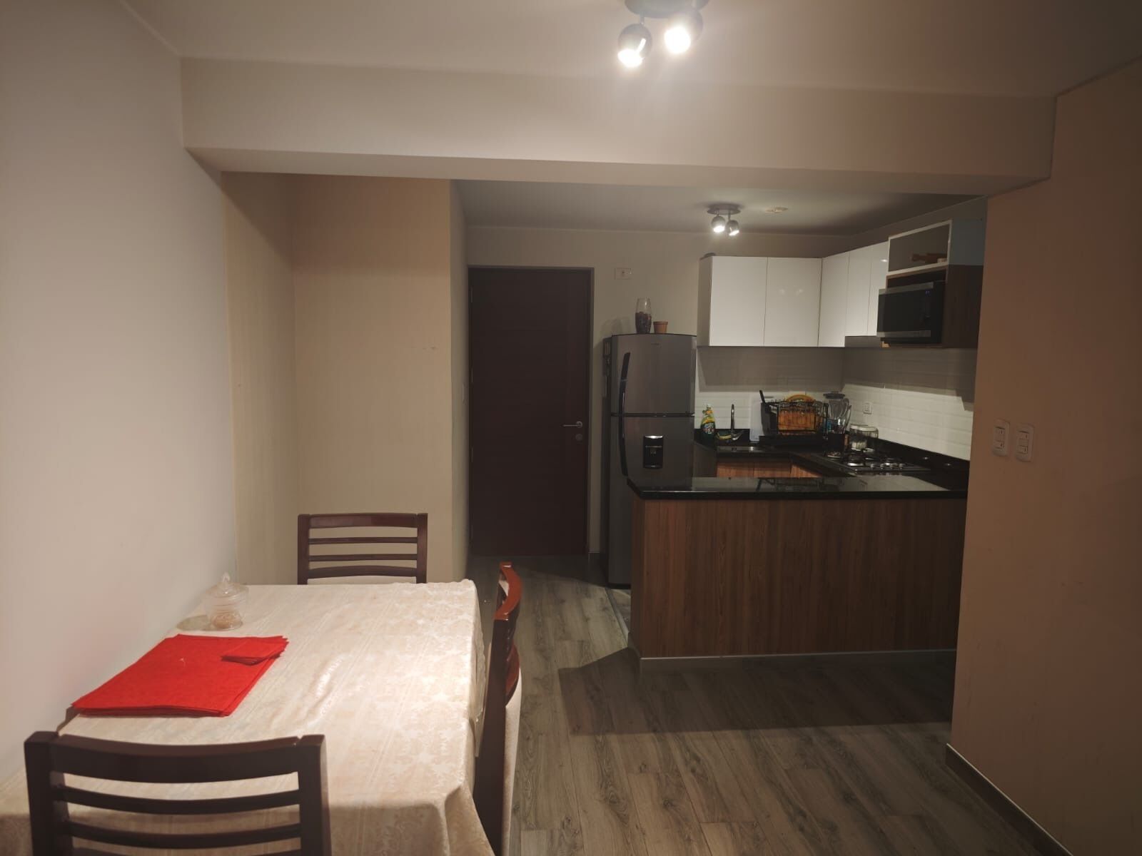 A compact kitchen with a refrigerator, microwave, and wooden cabinets.