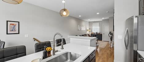 A modern kitchen with a central island, stainless steel appliances, and pendant lighting.