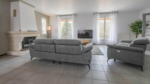 Ein Wohnzimmer mit Kamin, Fernseher und zwei grauen Sofas.