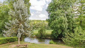 Ein Park mit Fluss, Picknicktisch und dichter Bepflanzung.