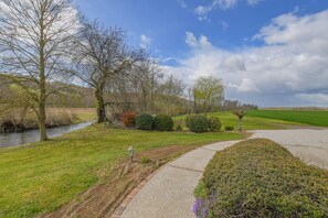 A riverside pathway with a lamp post, a grassy area, and a hedge. - Le Gîte de la Vanne - Saint-Benoît-sur-Vanne (SAINT BENOIST SUR VANNE)