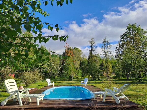 A swimming pool with lounge chairs and a wooden deck. - Country House in Pucón for 8 People: Large Garden, Stone Tub, Pool, and Grill (Pucón)