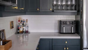 Una cocina moderna con armarios oscuros, una cafetera y un refrigerador.