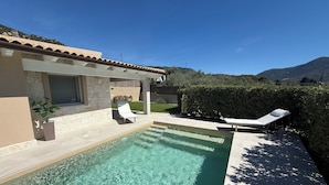 A swimming pool with lounge chairs, a stone wall, and a view of mountains. - A cozy home for relaxing moments, perfect for families or friends (Cuili Murvoni)
