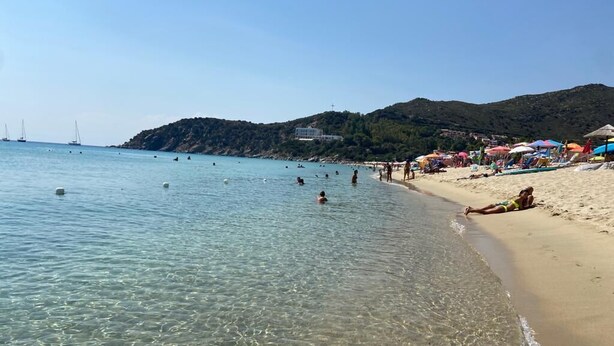 A beach with clear water, people swimming, and umbrellas on the sand. - A cozy home for relaxing moments, perfect for families or friends (Cuili Murvoni)