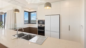 Una cuina moderna amb un rentaplat de superfície inox, forn de sobretaula i nevera.