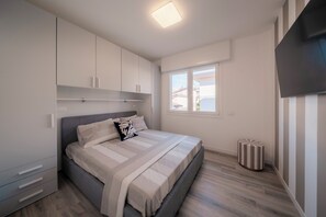 Ein Schlafzimmer mit Bett, Kleiderschrank, Fernseher und Fenster.