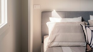 A bedroom with a bed, a wardrobe, and a window. - Sundown Living | New & Modern Apartment | 200 m from the beach | Balcony | Air conditioning (Lignano Sabbiadoro)