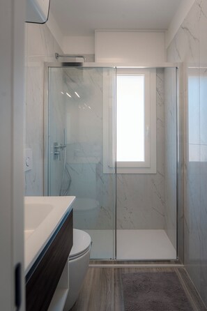 Ein modernes Badezimmer mit Duschkabine, Toilette und Waschtisch.