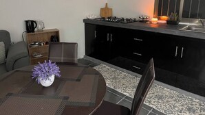 Ett modernt kök med en matplats, med ett runt bord dekorerat med en vas med blommor, en soffa och en köksö med inbyggda apparater.