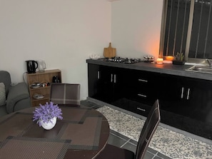 Una cocina moderna con comedor, que incluye una mesa redonda con un florero, un sofá y una encimera de cocina con electrodomésticos.