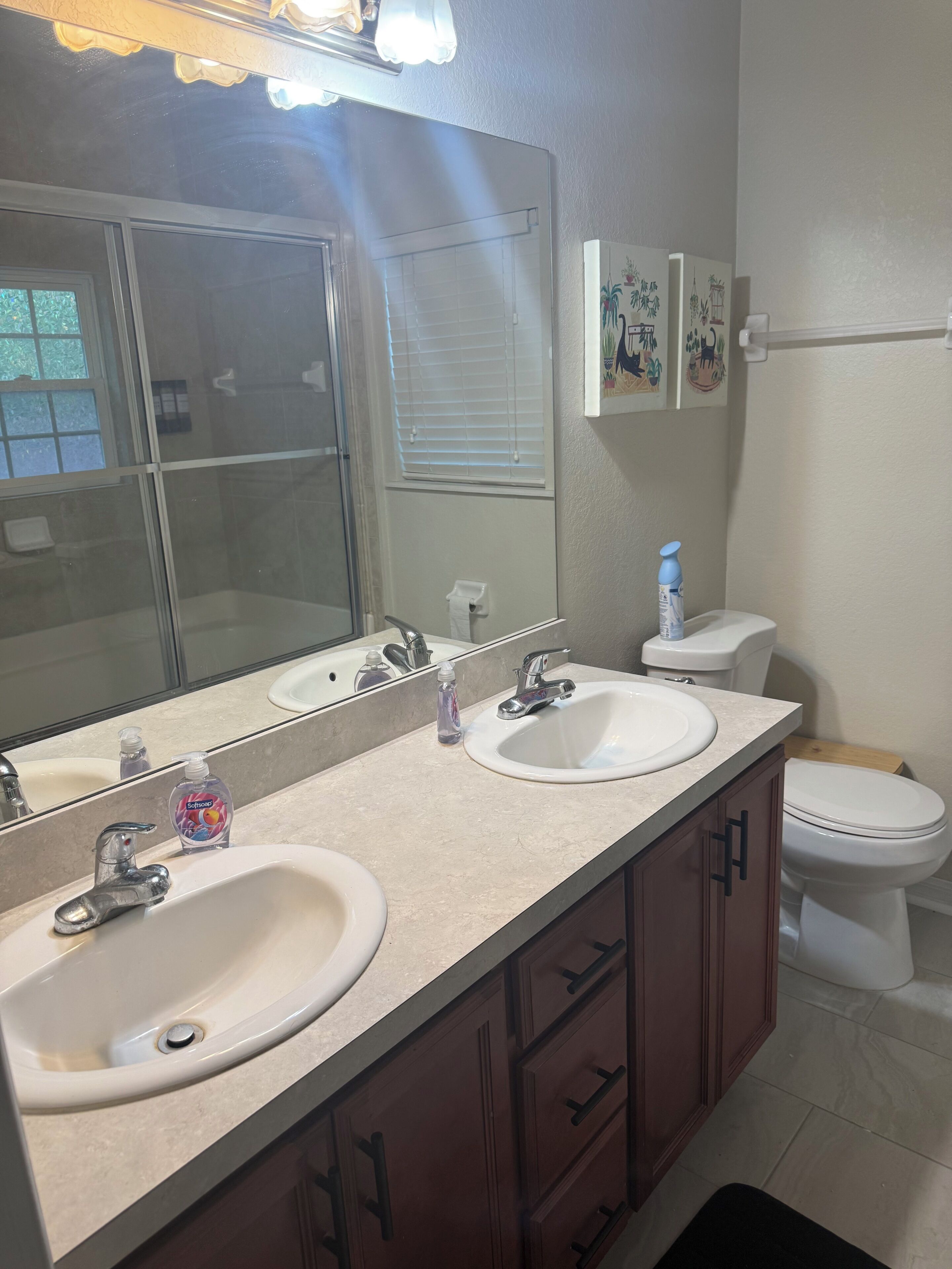 A bathroom with two sinks, a mirror, a toilet, and a shower.