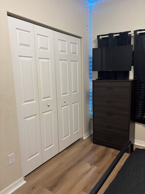 A room with a white closet, a dark dresser, and a blue LED light strip along the wall. - Quiet 3BR Gainesville Home Sleeps 8 (Gainesville)