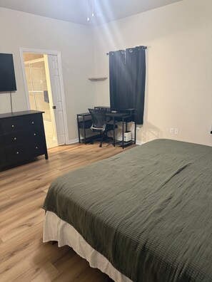 A bedroom with a bed, a desk with a chair, a dresser, and a television. - Quiet 3BR Gainesville Home Sleeps 8 (Gainesville)