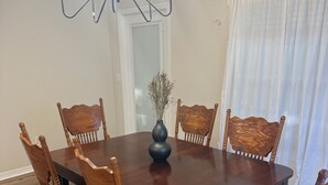 Un tavolo da pranzo con sei sedie, un vaso con piante secche e un lampadario.
