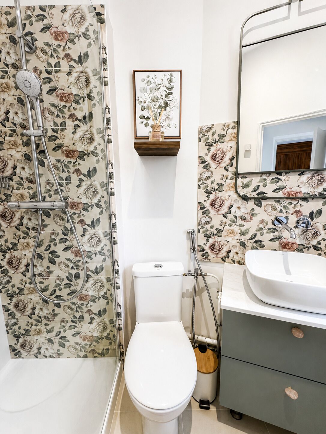 Ein Badezimmer mit Dusche, Toilette, Waschbecken und einem gerahmten Bild an der Wand.