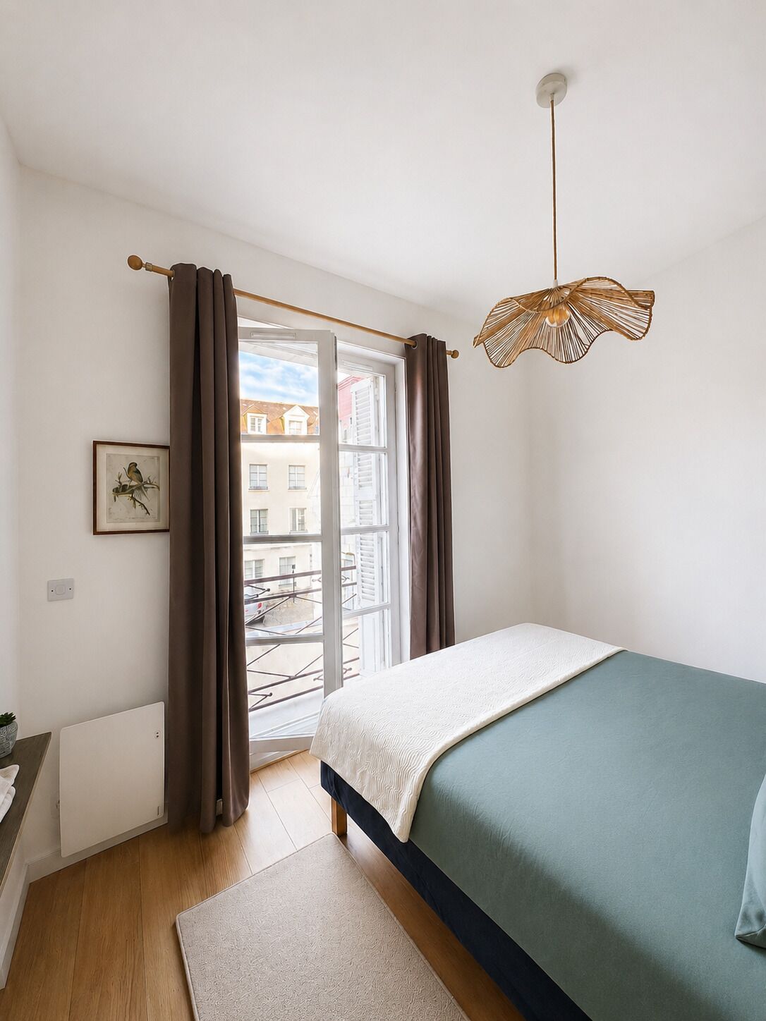 Un dormitorio con una cama, una ventana con cortinas, una lámpara colgante y un cuadro en la pared.
