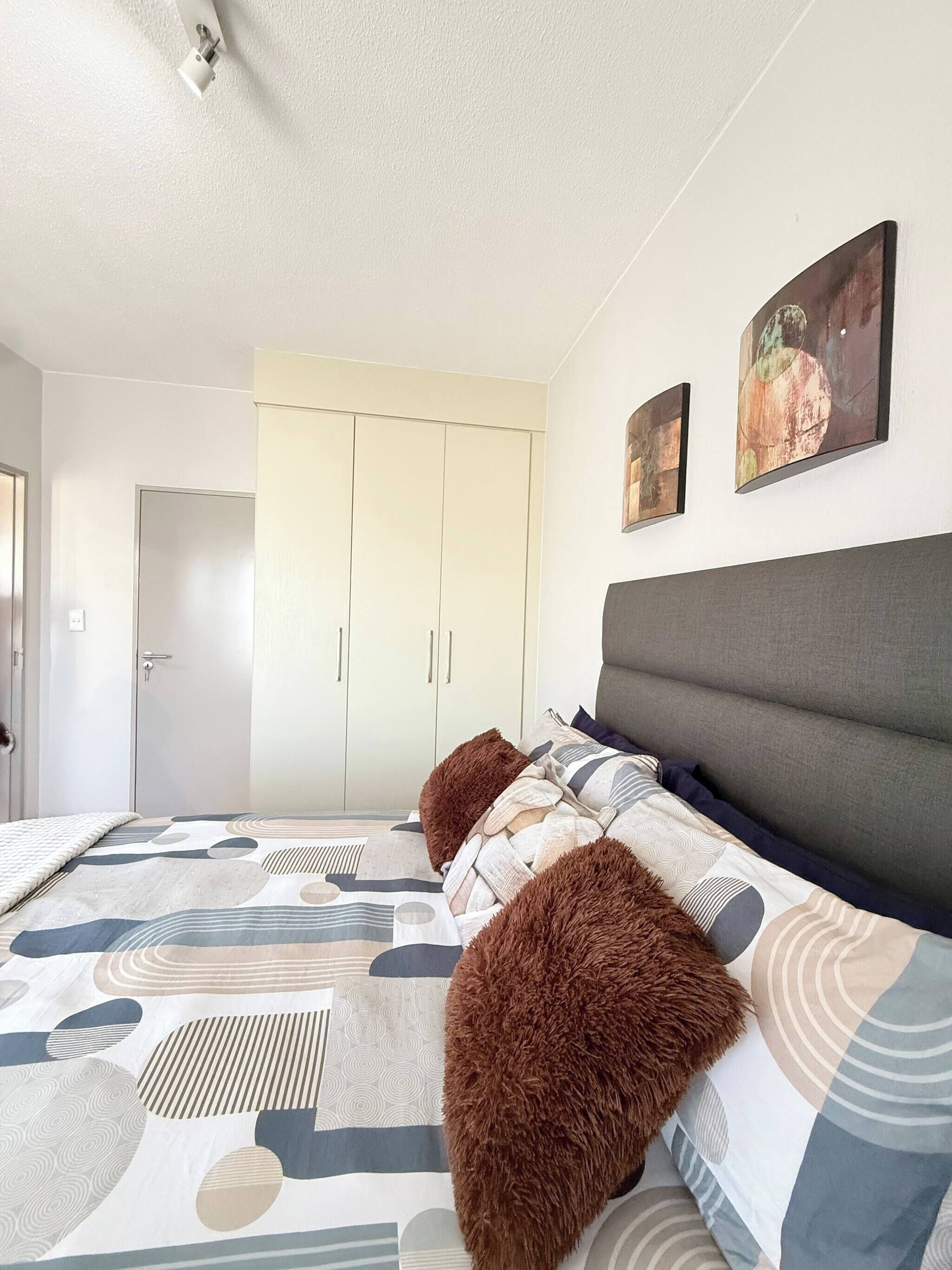 A bedroom with a bed, a wardrobe, and two paintings on the wall.