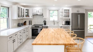 Eine moderne Küche mit weißen Schränken, einer Holztheke und einem eingebauten Backofen.