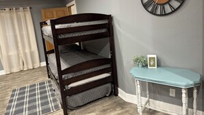 A bunk bed with three levels, a round wall clock, a small table with a picture, and a plaid rug. - If you want quiet, peaceful, & a beautiful sunset, you’ll love House on the Hill (Media)