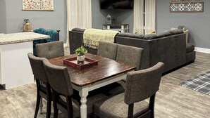 A modern living room with a dining area, grey walls, a flat-screen TV, and a grey sofa. - If you want quiet, peaceful, & a beautiful sunset, you’ll love House on the Hill (Media)
