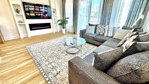 A modern living room with a sofa set, a flat-screen TV, and a coffee table. - Prime UTSW | 3BR Home + Patio+Garage (Dallas)