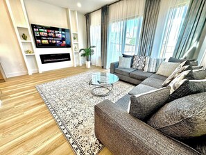 A modern living room with a sofa set, a flat-screen TV, and a coffee table. - Prime UTSW | 3BR Home + Patio+Garage (Dallas)