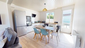 A modern kitchen with a dining area, a sofa, and a view of the sea. - T'y Braz – House with garden & pétanque, 800m² lot (Bretignolles-sur-Mer)