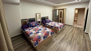 A bedroom with two beds, a wardrobe, and a mirror. - Diarna Lartin Residency 1 (Marsa Matrouh Governorate)
