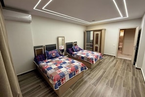 A bedroom with two beds, a wardrobe, and a mirror.