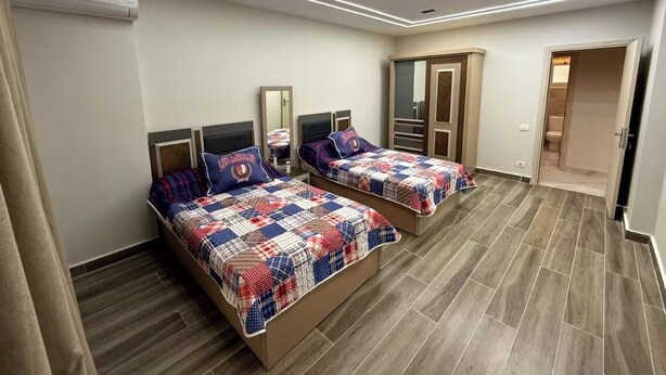 A bedroom with two beds, a wardrobe, and a mirror. - Diarna Lartin Residency 1 (Marsa Matrouh Governorate)