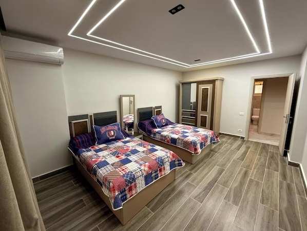 A bedroom with two beds, a wardrobe, and a mirror.