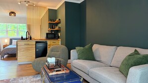 Una sala moderna con sofá, un comedor con microondas y una cocina con estantes de madera.