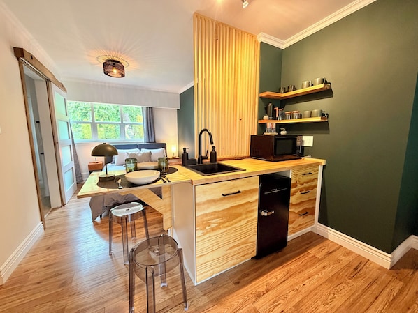 Una cocina moderna con encimera de madera, microondas integrado y un lavabo.