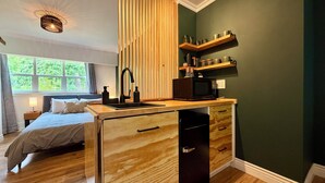 Un dormitorio acogedor con un ventanal grande, una cama de madera, una mesita de noche y una lámpara de noche.