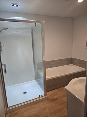 Un baño con ducha acristalada, bañera y retrete.